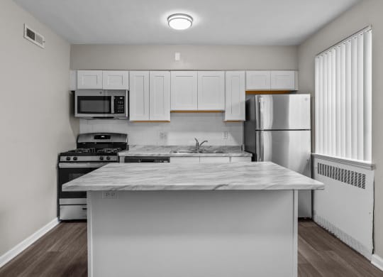 an empty kitchen with white cabinets and stainless steel appliances and a marble counter top