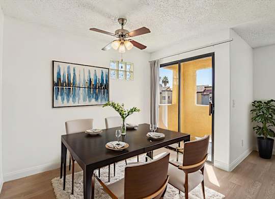 A dining room with a table set for two and a ceiling fan.