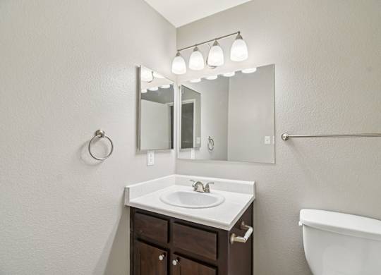 A bathroom with a sink, mirror, and toilet.