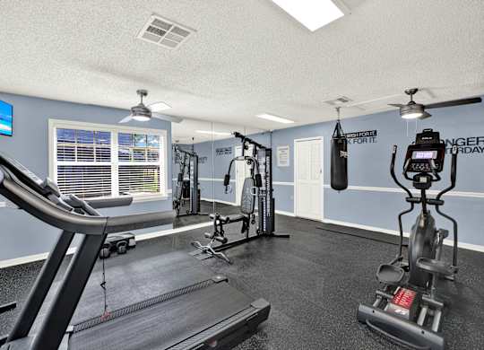 A gym with a treadmill, weights, and a television.
