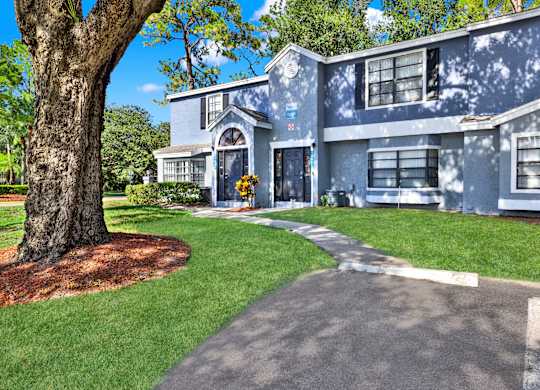 A blue house with a tree in front.