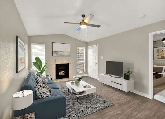 A living room with a blue couch, a fireplace, and a television. at Seacrest Apartments, Garland, Texas