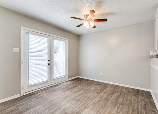 an empty living room with a ceiling fan and a door at Falls on Clearwood Apartments, Richardson, TX, Texas