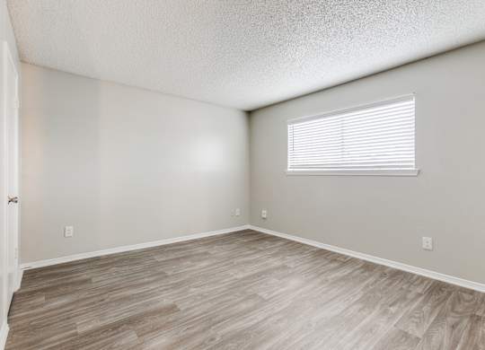 the spacious living room with wood flooring and a window at Falls on Clearwood Apartments, Richardson, TX, Texas