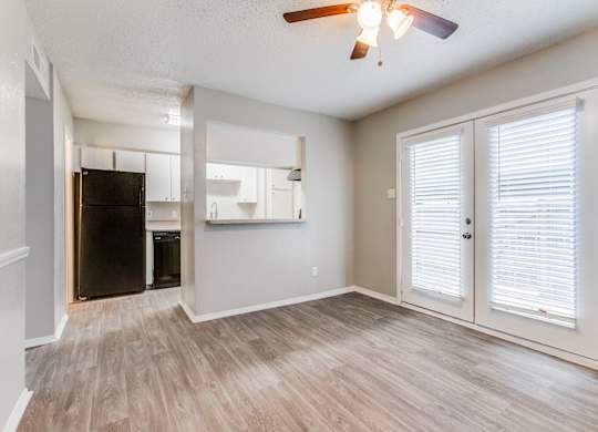 an empty living room with a kitchen and a ceiling fan at Falls on Clearwood Apartments, Richardson, TX, Texas