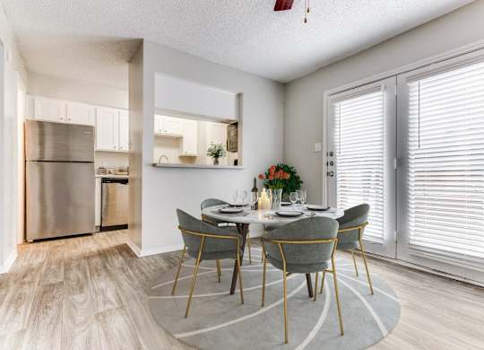 a dining room with a table and chairs and a kitchen with stainless steel appliances at Falls on Clearwood Apartments, Richardson, TX, Texas