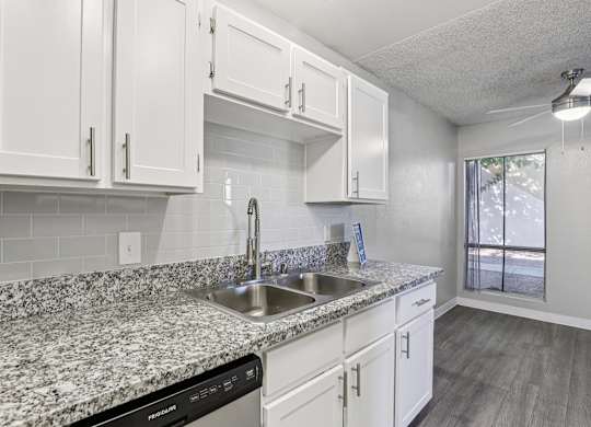 A kitchen with granite countertops and white cabinets.