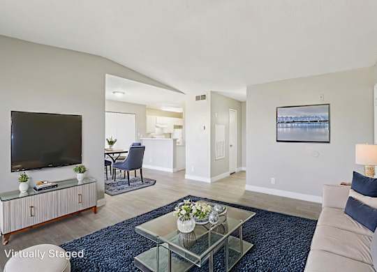 A living room with a television, a sofa, and a glass coffee table.