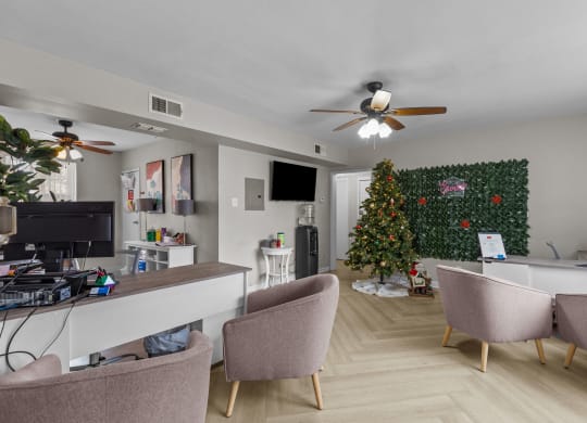 a living room with a christmas tree and a desk and chairs