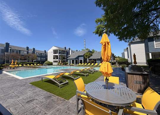 A pool area with yellow chairs and umbrellas.