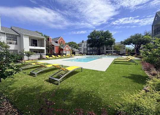 A swimming pool surrounded by a grassy area and benches.