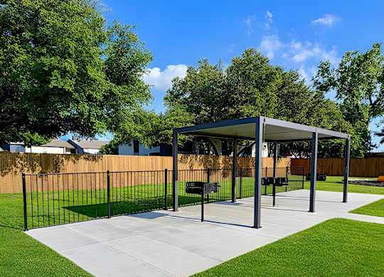 A park with a white pavement and a black fence.