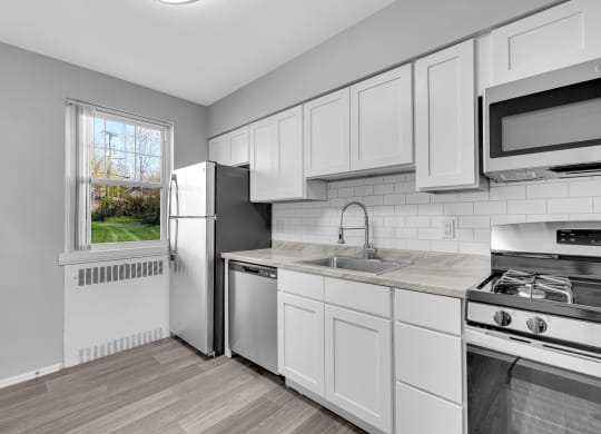 a kitchen with white cabinets and stainless steel appliances at Hampton Gardens, Saint Louis