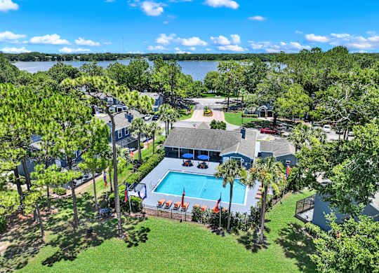 A bird's eye view of a house with a swimming pool surrounded by trees.
