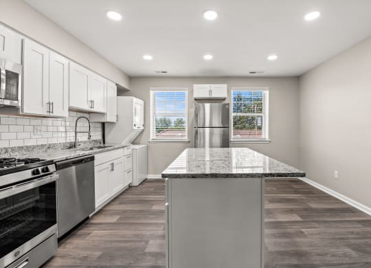 a kitchen with white cabinets and a large island with granite countertops at Hampton Gardens, Missouri, 63139
