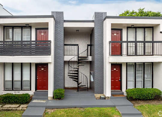 A modern two-story house with a red door and a black metal staircase.