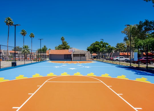 A basketball court with a blue and orange surface and white lines.