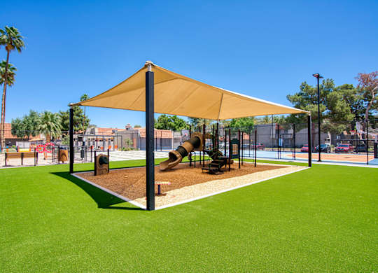 A playground with a yellow canopy and a slide.