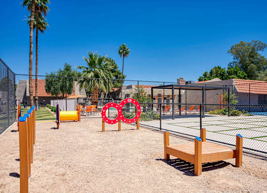 A playground with a wooden bench, a fence, and a swing set.