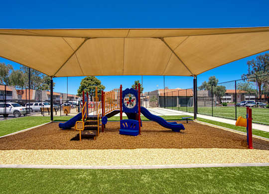 A playground with a blue slide and yellow and red play equipment.
