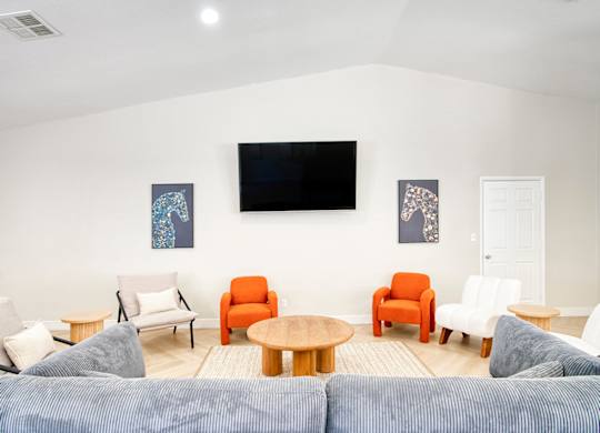A living room with a blue couch and a television on the wall.