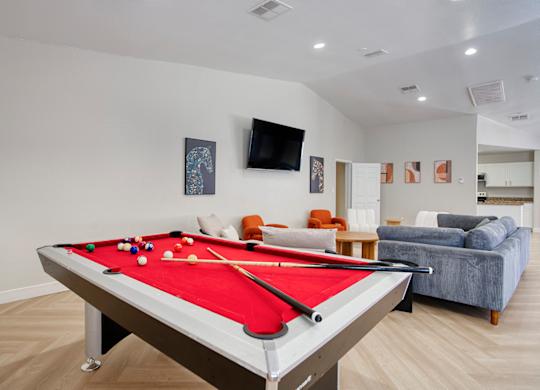 A pool table is in the middle of a room with a couch and a television.