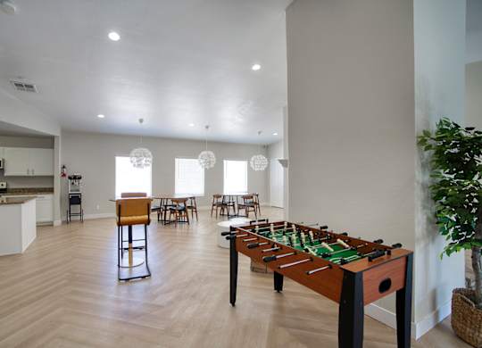 A foosball table is in the middle of a kitchen and dining area.