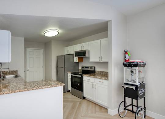 A kitchen with white cabinets and granite countertops.