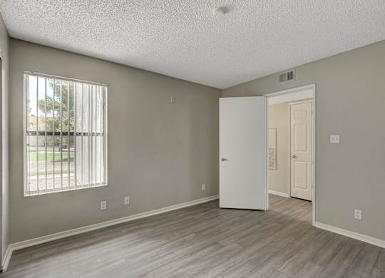 A room with a white door and a window with blinds.