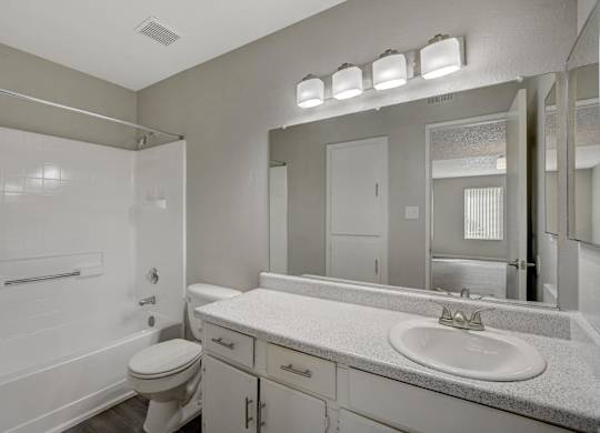 A white bathroom with a toilet, sink, and mirror.