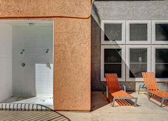 A bathroom with a walk-in shower and two chairs.