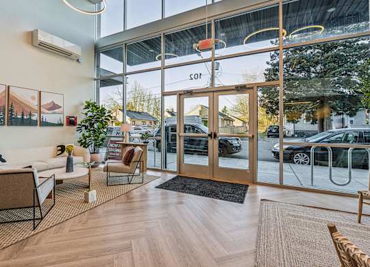 A modern office lobby with a glass wall and a black and white chair.