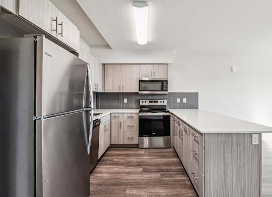 A modern kitchen with a stainless steel refrigerator and wooden flooring.