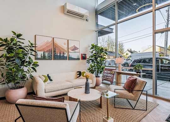 A living room with a couch, chair, and potted plant.