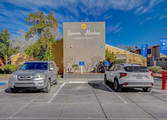Two cars are parked in front of a building with a sign that reads