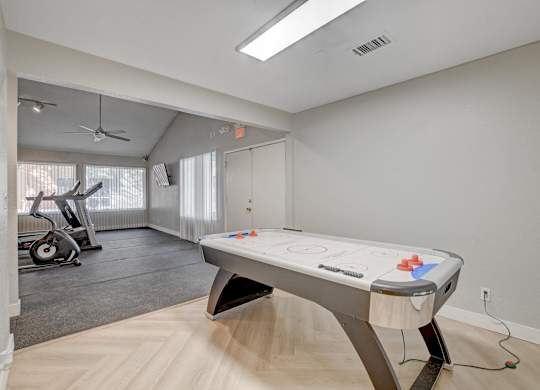 A pool table in a room with a fan and exercise equipment.