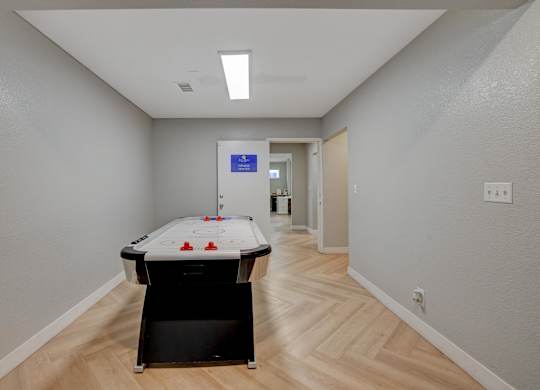 A pool table in a room with light wood flooring and white walls.