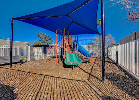 A playground with a blue canopy and a green slide.