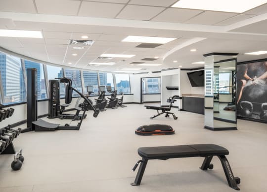 a large fitness room with exercise equipment and a large window overlooking the city at Vision on Lombard, Baltimore, MD 21201