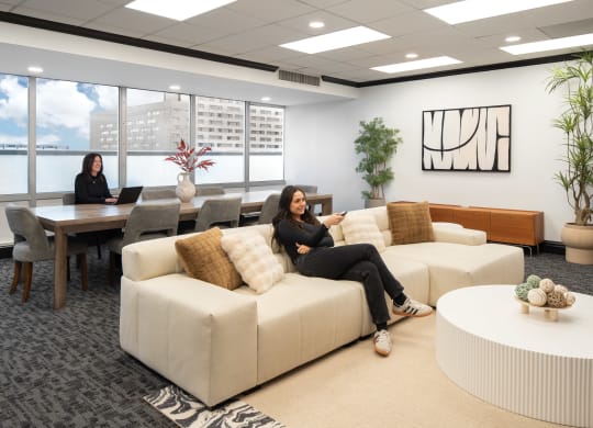 two women sit on a couch in an office lounge area at Vision on Lombard, Baltimore, MD 21201