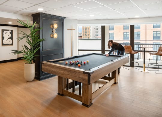 a woman playing a pool table in a game room at Vision on Lombard, Baltimore, MD 21201