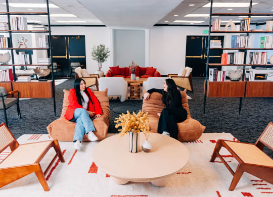 two women sitting on couches in a living room with a coffee table at Vision on Lombard, Baltimore, MD 21201