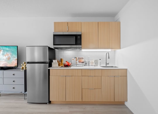 a kitchen with wooden cabinets and a stainless steel refrigerator at Vision on Lombard, Baltimore, MD 21201