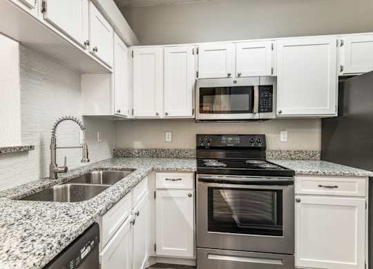 a kitchen with white cabinets and granite countertops at Foxborough Apartments, Irving, Texas