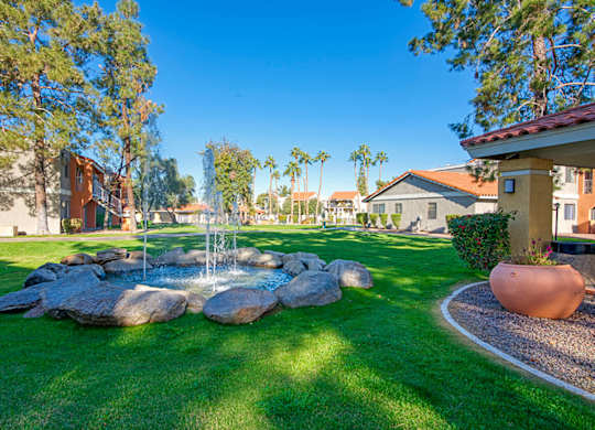 A garden with a fountain and a large pot.
