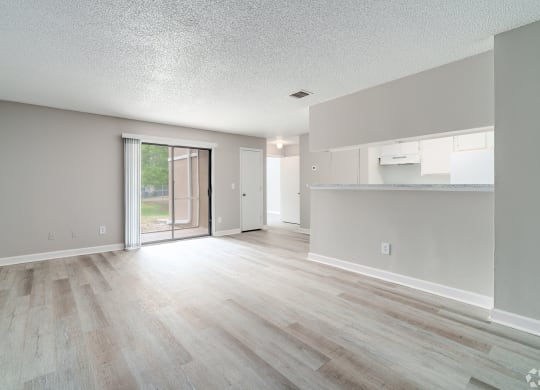 an empty living room and kitchen with a sliding glass door to a patio at Village Lakes, Orlando, FL, 32808