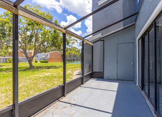 the patio of a building with glass doors and a grass field