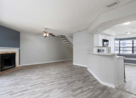 an empty living room with a fireplace and a ceiling fan