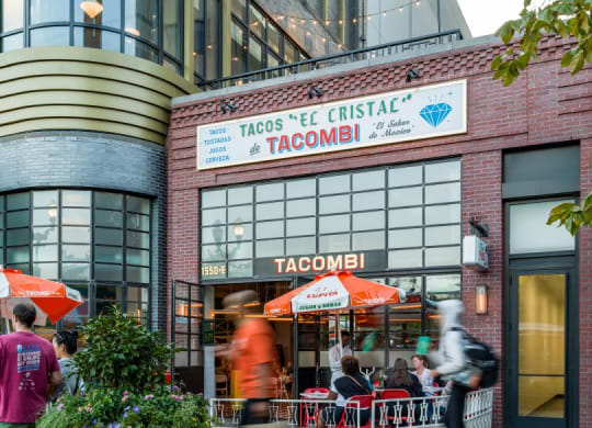 people walking past a taco restaurant in front of a building at The Grace and Reva, Arlington, 22202