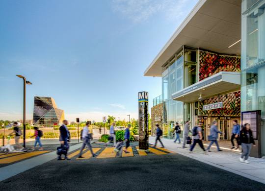 A group of people are walking on a sidewalk in front of a building.
